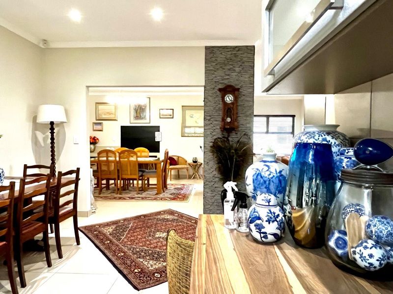 An open-plan living and dining area featuring tiled floors, recessed lighting, and a decorative stone-cladding feature wall connecting the kitchen and dining spaces.