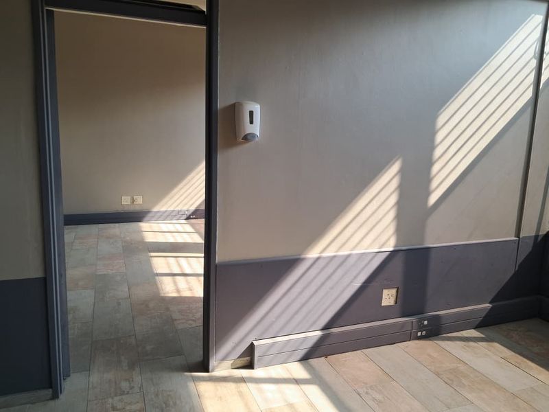 An empty office space featuring tiled flooring, neutral wall tones, and integrated electrical points, suitable for a professional workspace setup.
