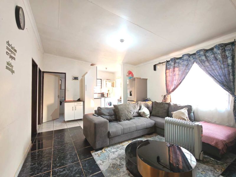 Open plan living area featuring tiled flooring and direct access to the kitchen and hallway.
