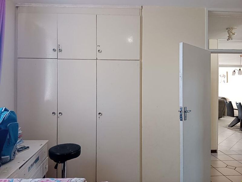 Bedroom featuring floor-to-ceiling built-in cupboards with a neutral finish and an internal door leading to the main living area.