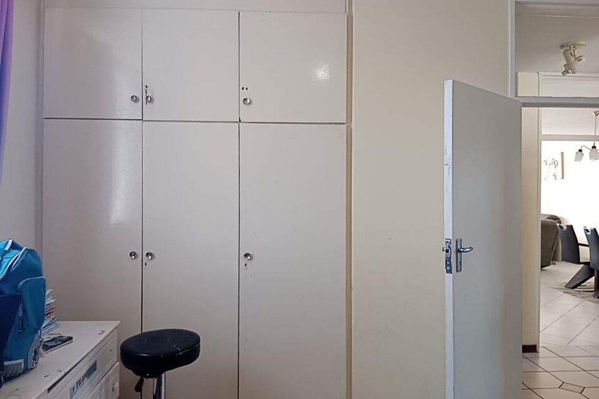 Bedroom featuring floor-to-ceiling built-in cupboards with a neutral finish and an internal door leading to the main living area.