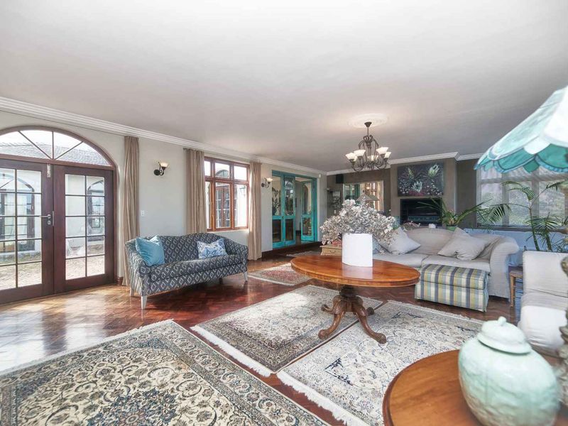 Spacious living room featuring classic parquet flooring, elegant arched french doors, and a built-in fireplace, offering a warm and inviting atmosphere.