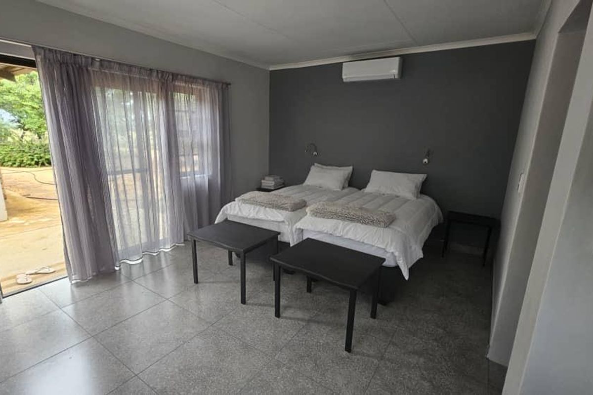 A well-maintained bedroom featuring tiled flooring, a split-system air conditioner, and a sliding glass door providing direct access to the outdoor area.