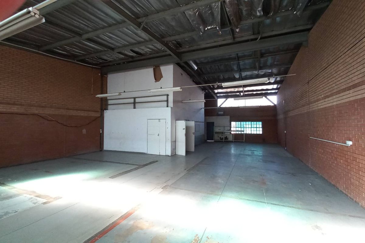 Spacious industrial warehouse unit featuring exposed brick walls, high-clearance steel roof structure, and concrete flooring, suitable for storage or light manufacturing operations.