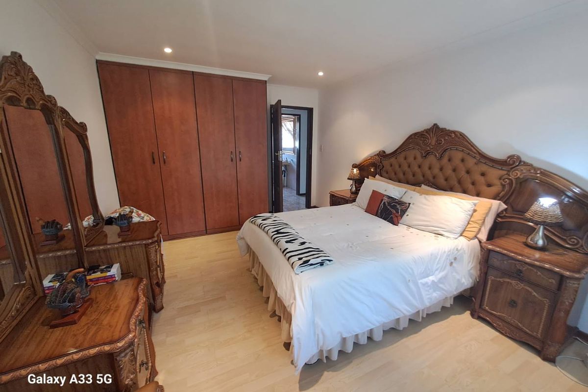 Spacious bedroom featuring built-in wooden cupboards, light-toned laminate flooring, and recessed ceiling lighting.