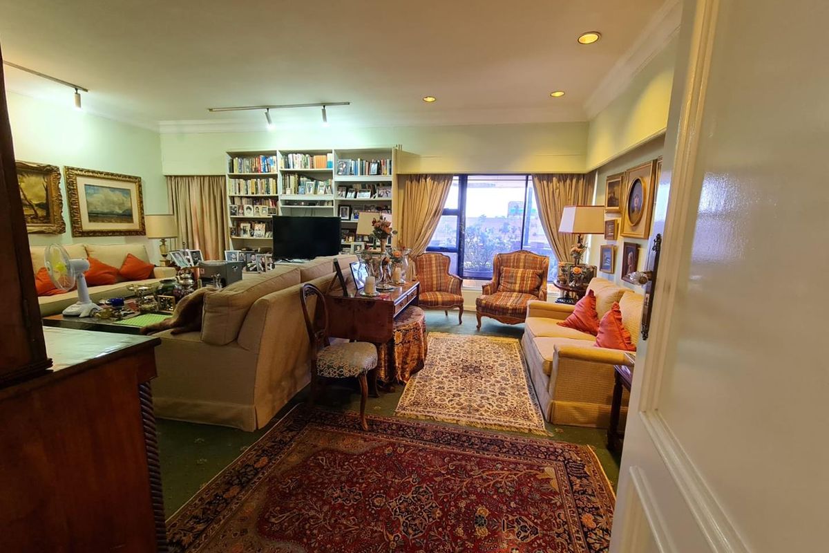 Spacious living room featuring built-in floor-to-ceiling shelving, recessed lighting, and large windows providing natural light and an urban view.