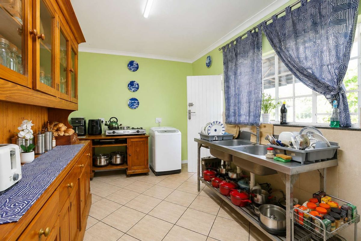 Functional kitchen featuring a stainless steel double sink, tiled flooring, and ample storage space with a mix of wooden cabinetry and open shelving.