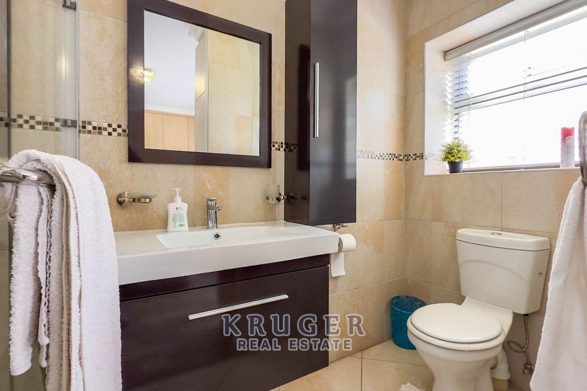 A well-maintained bathroom featuring a modern vanity with integrated basin, wall-mounted storage cabinet, tiled walls, and a toilet.