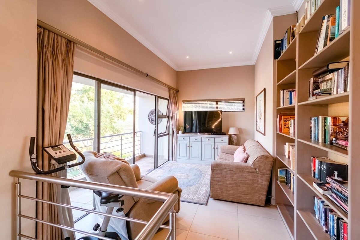 A cozy living area featuring built-in floor-to-ceiling shelving, tiled flooring, and large sliding glass doors that open onto a private balcony.