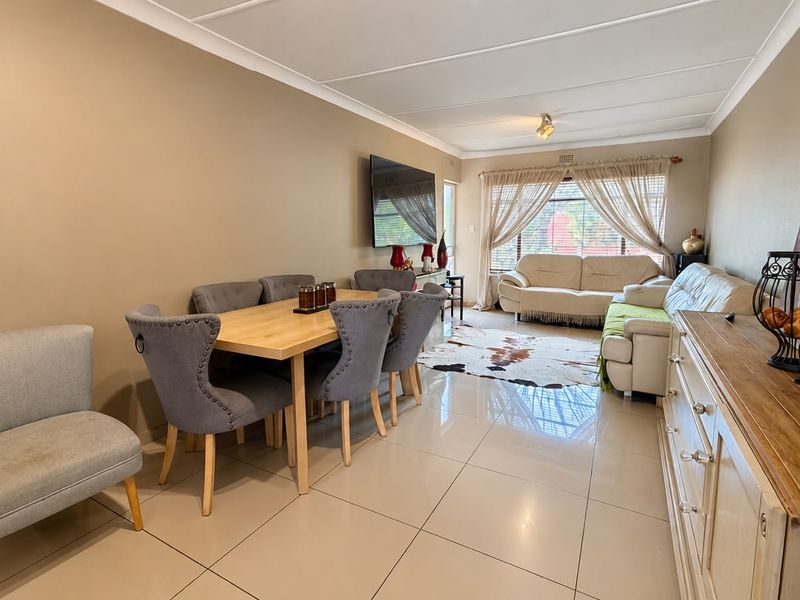 Spacious open-plan living and dining area featuring neutral wall tones, large format floor tiles, and a coved ceiling with ample natural light.