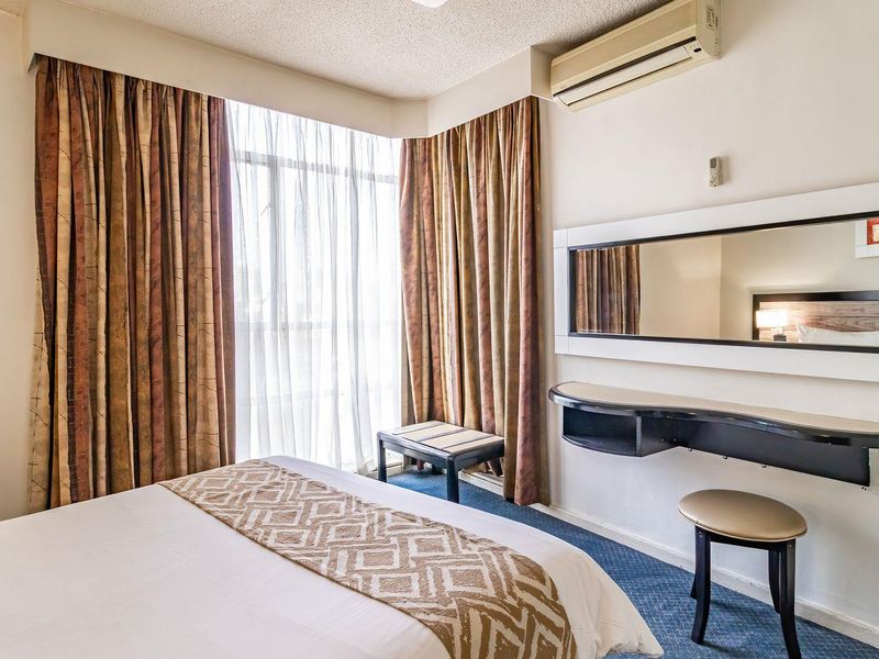 A bedroom featuring a wall-mounted air conditioning unit, a built-in vanity shelf with mirror, and carpeted flooring.