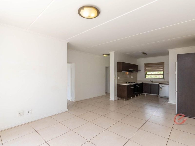 Spacious open-plan living area featuring tiled floors and a functional kitchen with built-in cabinetry, hob, oven, and extractor fan.
