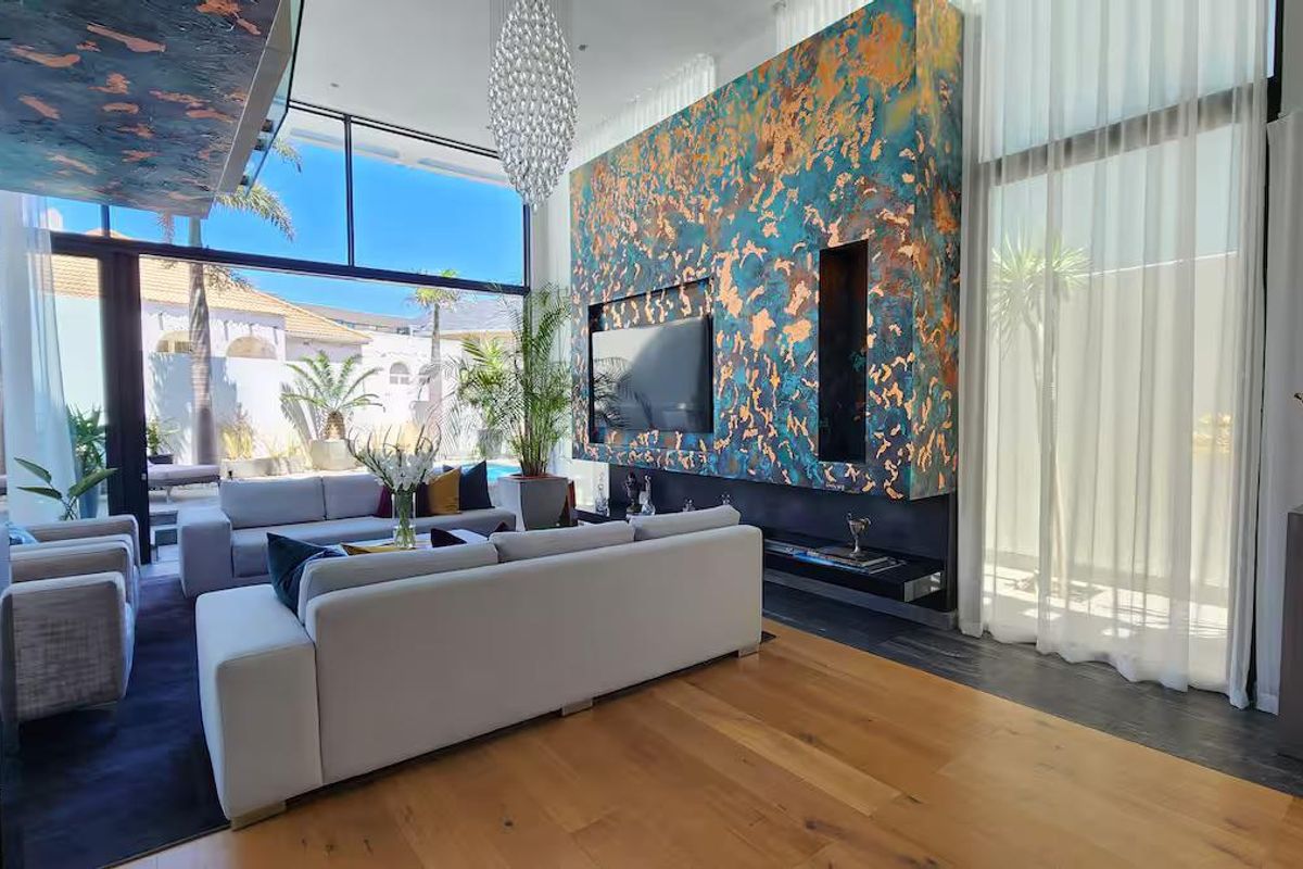 Spacious living room featuring high ceilings, hardwood flooring, floor-to-ceiling windows, and a striking decorative feature wall with a built-in fireplace.