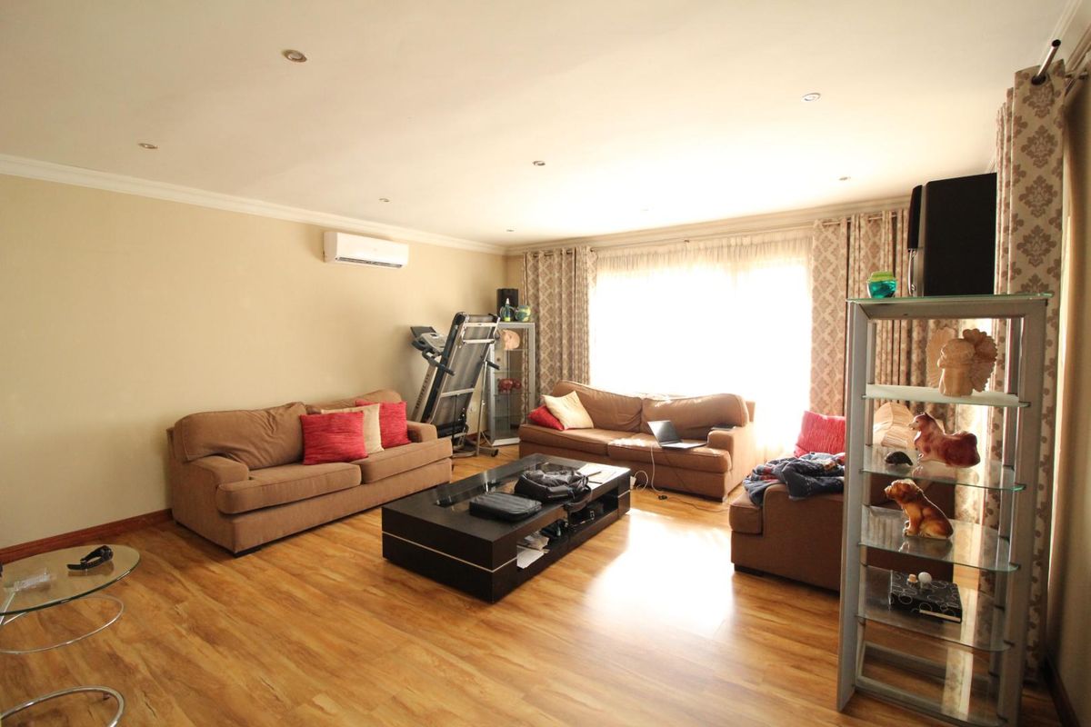 Spacious living room featuring wood-look laminate flooring, recessed ceiling lighting, and a wall-mounted air conditioning unit.