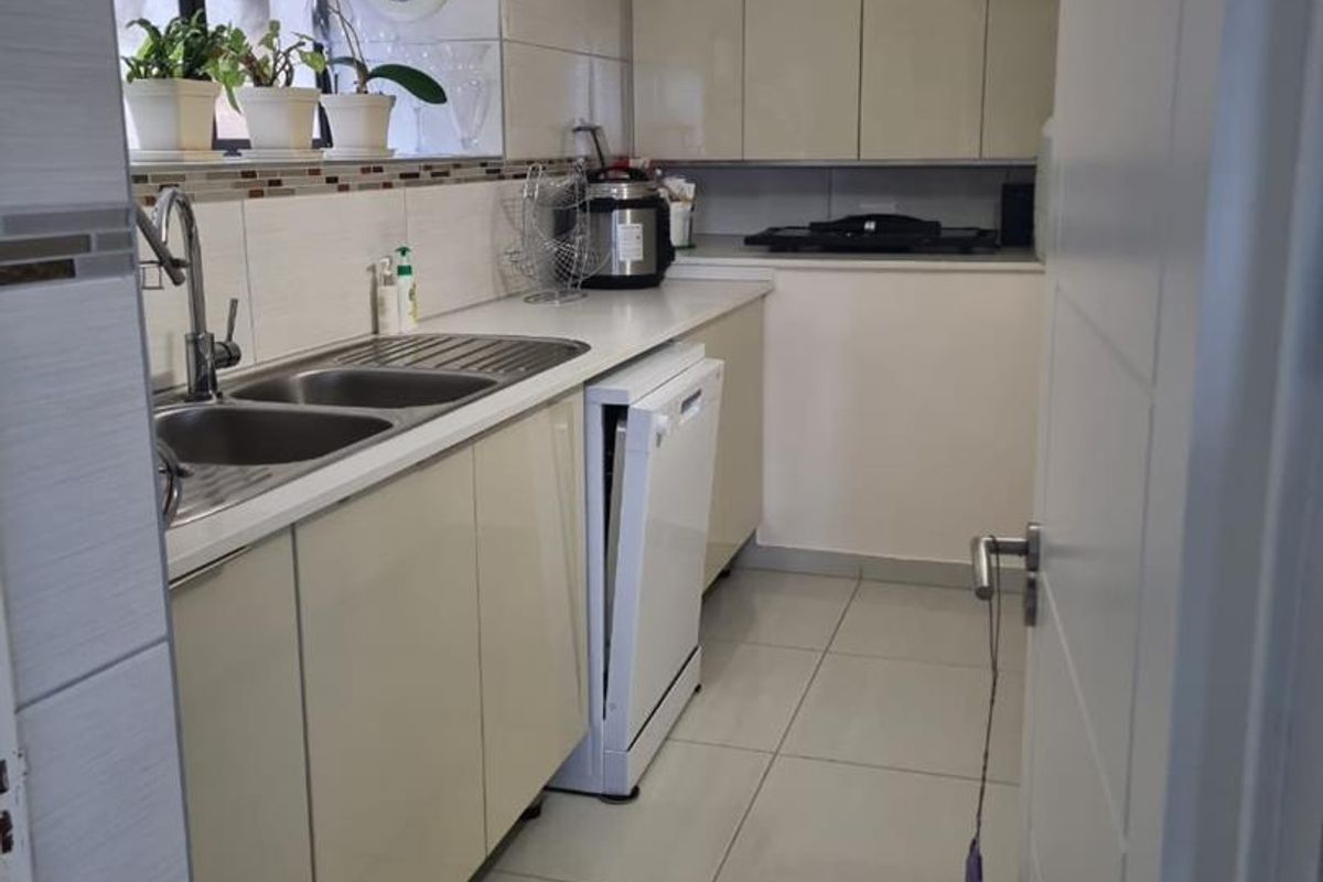 A functional kitchen featuring neutral built-in cabinetry, tiled flooring, a double bowl stainless steel sink, and a tiled backsplash.