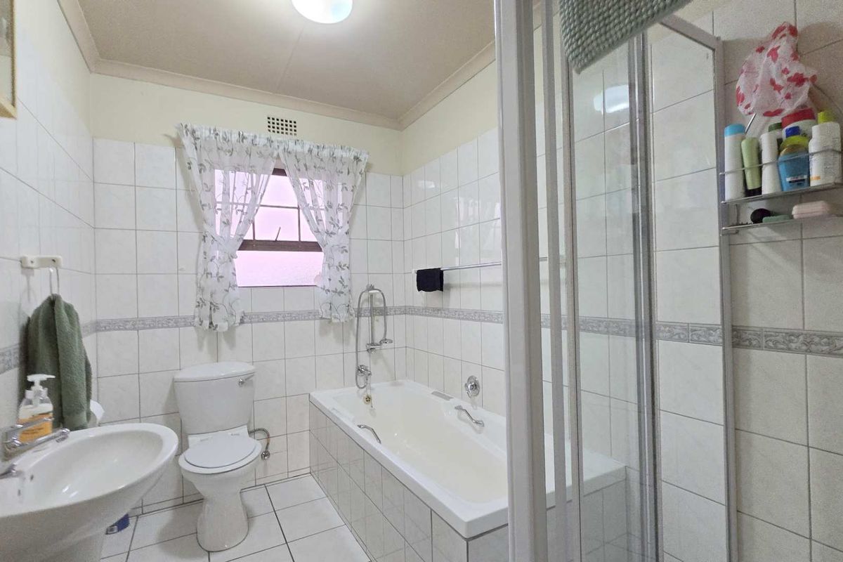 A functional bathroom featuring a built-in bathtub, separate shower enclosure, pedestal basin, and toilet with classic white wall tiling.