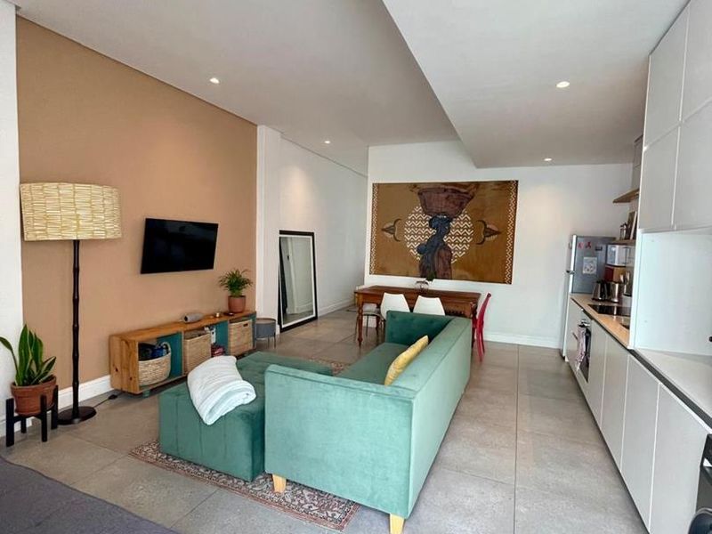 Modern open-plan living area featuring tiled floors, recessed lighting, and a sleek, contemporary kitchen with integrated cabinetry.