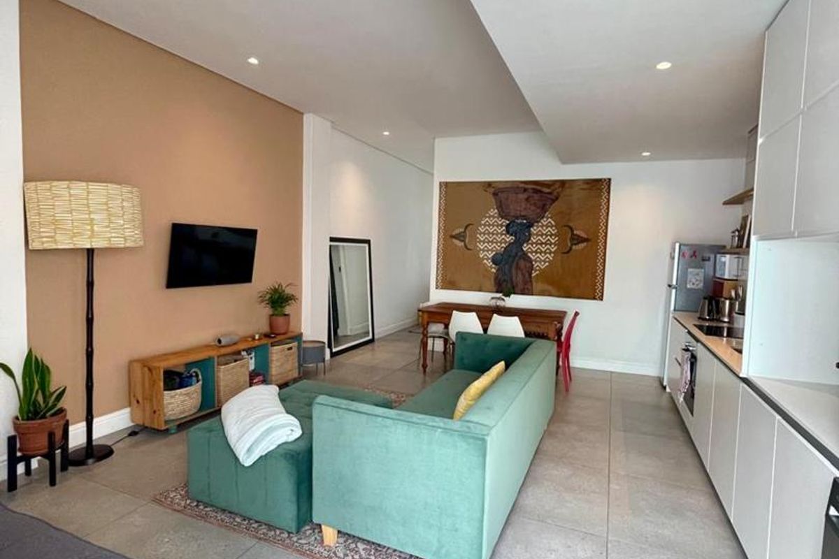 Modern open-plan living area featuring tiled floors, recessed lighting, and a sleek, contemporary kitchen with integrated cabinetry.