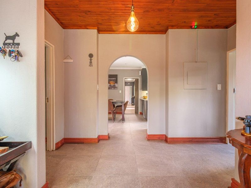 A well-maintained hallway featuring a warm timber ceiling, tiled flooring, and a central archway leading through to the living and kitchen areas.