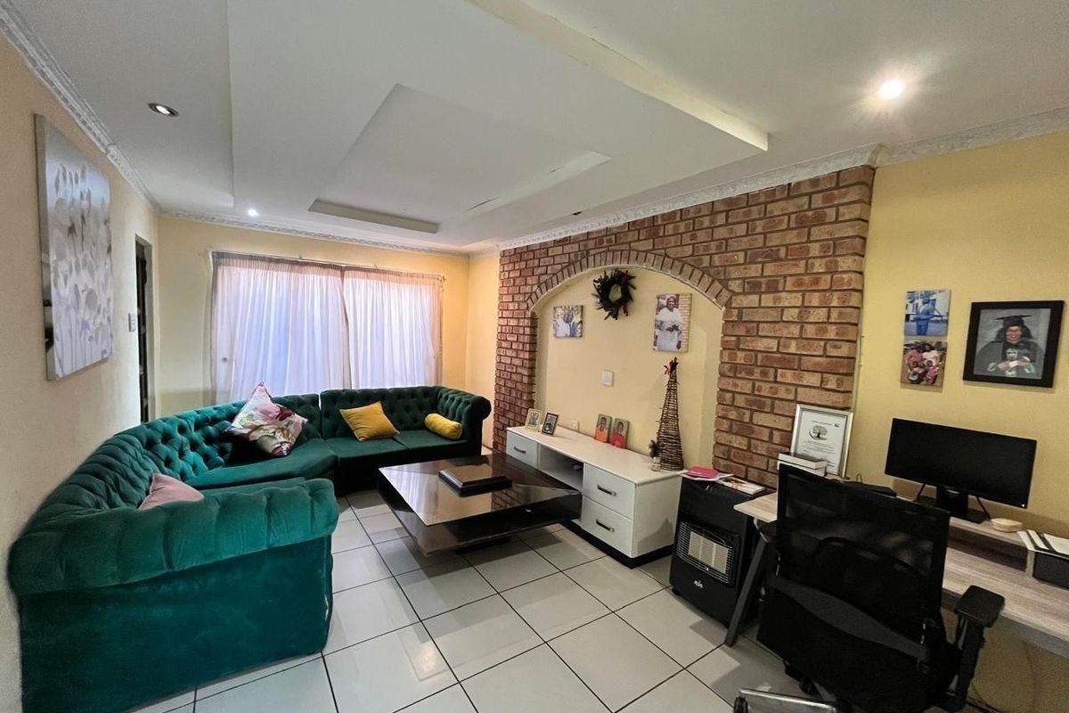 A living room featuring a prominent brick archway feature wall, recessed ceiling lighting, and neutral tiled flooring throughout the space.
