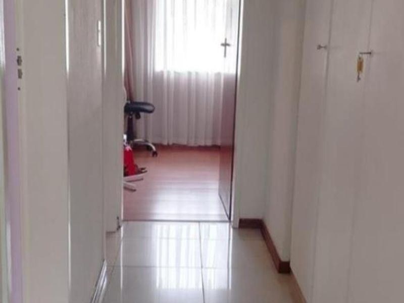 A functional hallway featuring tiled flooring and built-in storage cupboards, providing access to adjacent rooms.