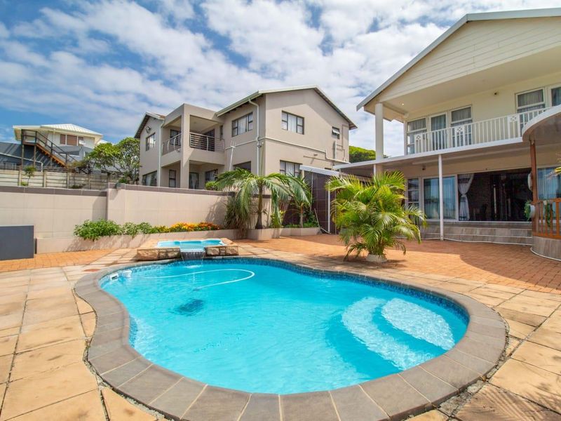 Outdoor entertainment area featuring a swimming pool with an integrated raised spa, surrounded by paved patio space and a covered veranda.