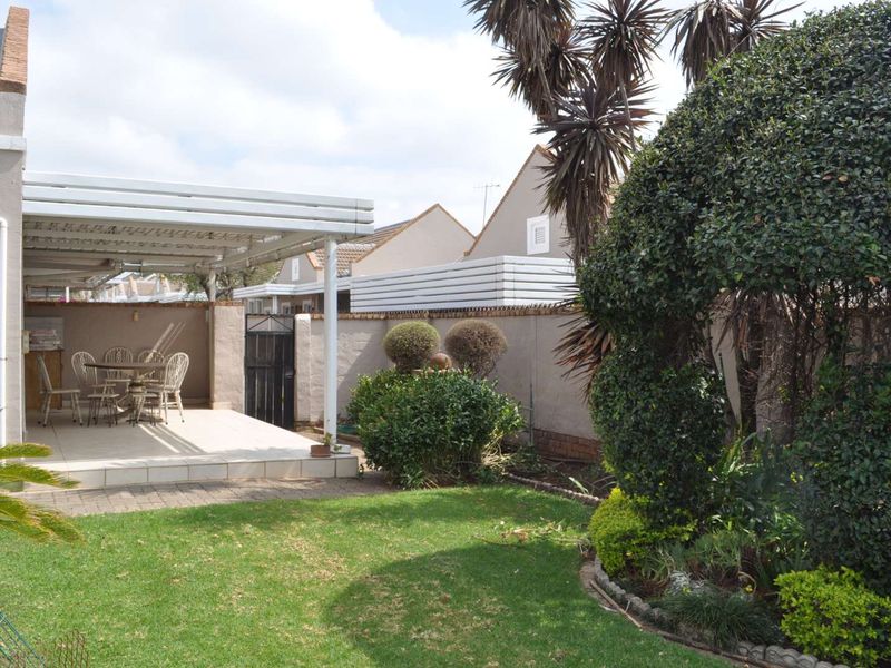 A private rear garden featuring a paved covered patio area, established landscaping, and secure boundary walls, ideal for outdoor relaxation.