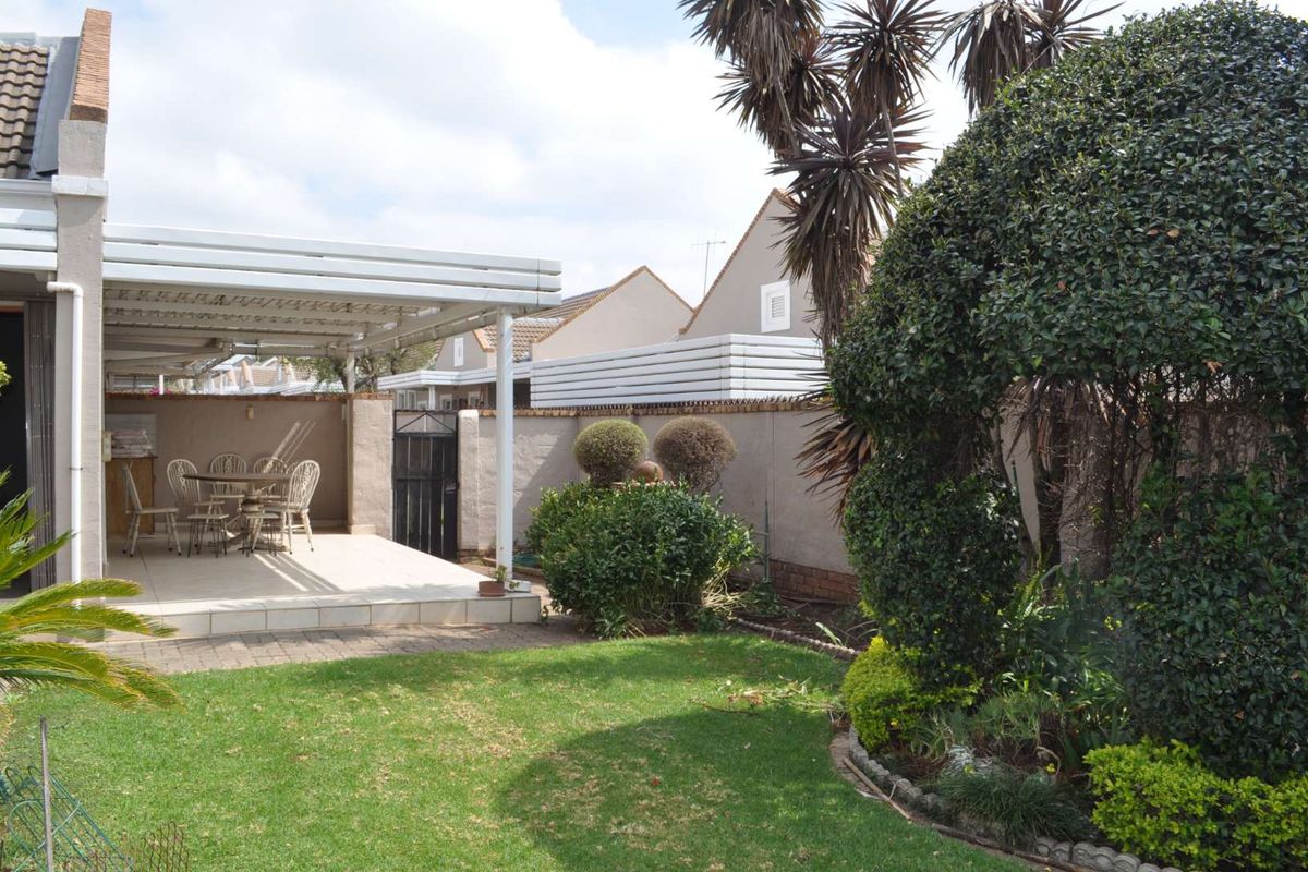 A private rear garden featuring a paved covered patio area, established landscaping, and secure boundary walls, ideal for outdoor relaxation.