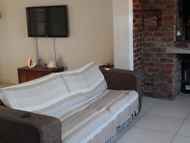 A living room featuring tiled flooring and a prominent exposed brick fireplace, offering a cozy and functional space.