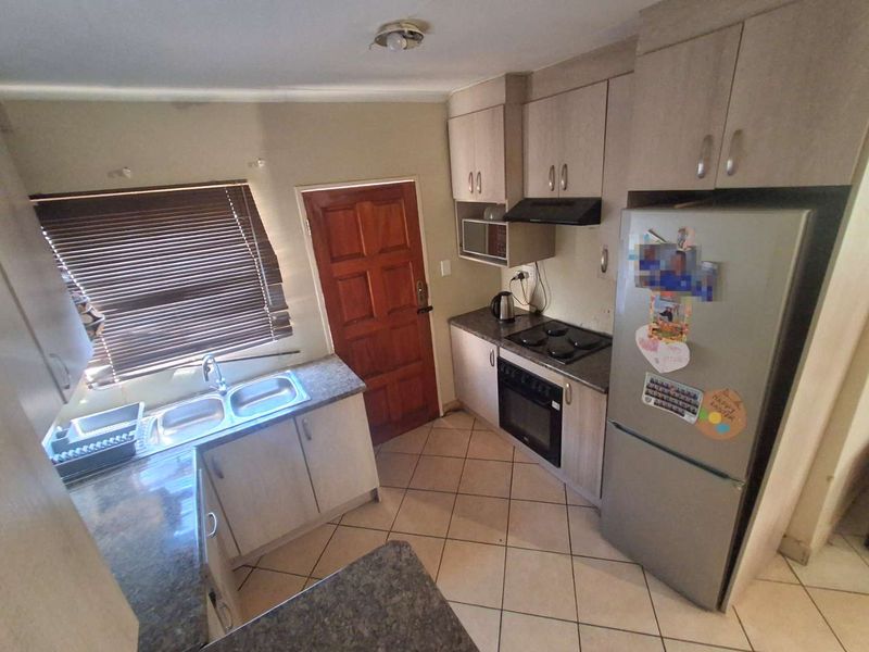 Functional kitchen featuring laminate cabinetry, built-in oven with hob, extractor fan, double bowl sink, and ceramic tile flooring.