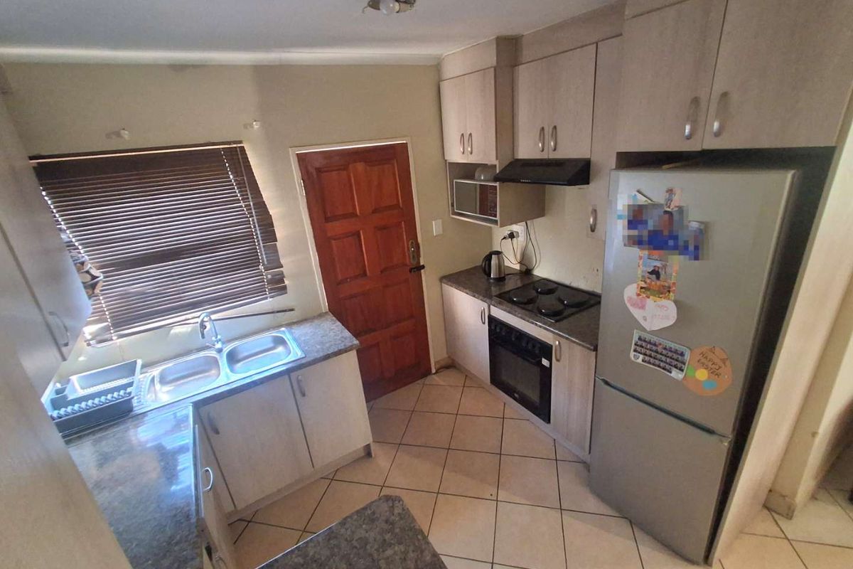 Functional kitchen featuring laminate cabinetry, built-in oven with hob, extractor fan, double bowl sink, and ceramic tile flooring.
