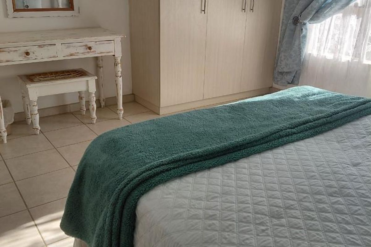 A bedroom featuring built-in light wood cabinetry and tiled flooring, offering a functional and neutral living space.