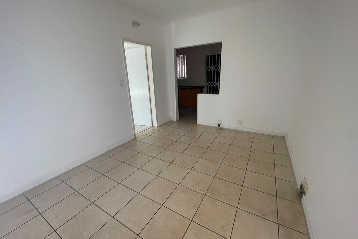 An empty living area featuring neutral ceramic floor tiles, providing a blank canvas for interior design and renovation.