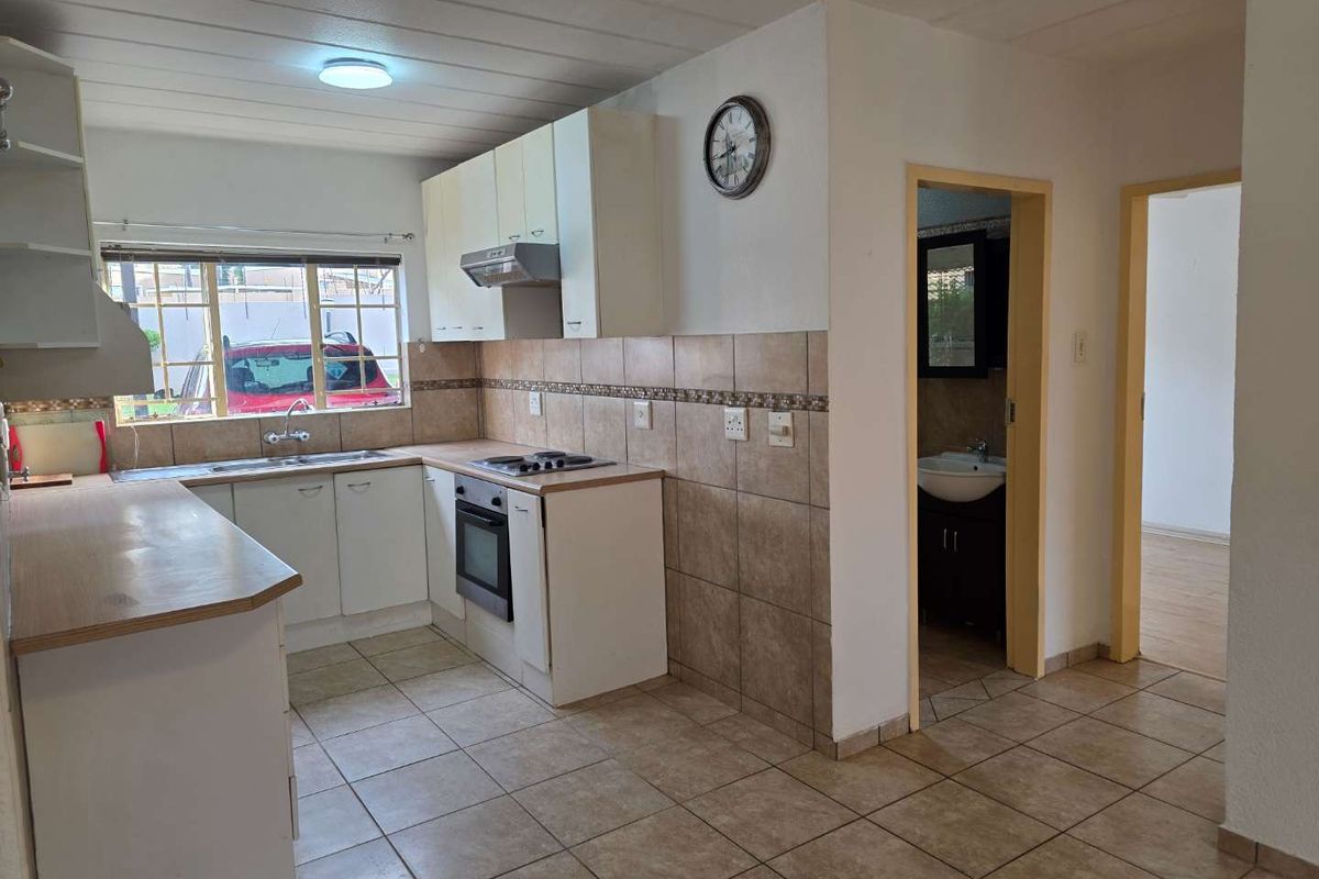 Functional kitchen featuring built-in cabinetry, integrated oven and hob, tiled splashbacks, and tiled flooring, with direct access to adjacent rooms.