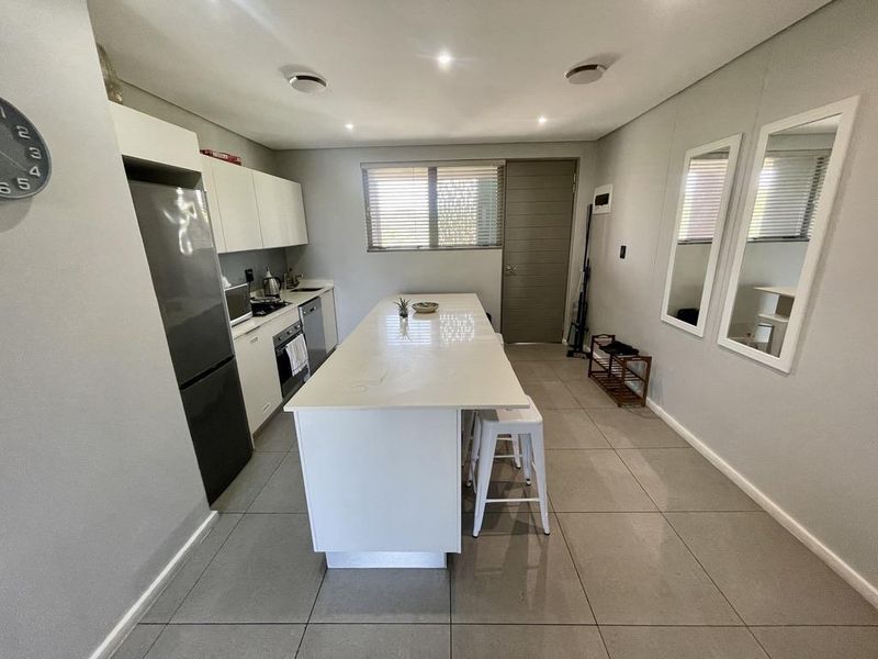 Modern kitchen featuring a central island with quartz countertops, built-in cabinetry, integrated appliances, and sleek tiled flooring.