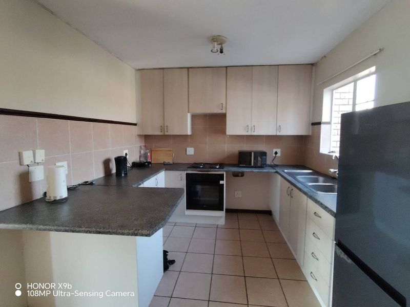 Functional kitchen featuring laminate cabinetry, stone-look countertops, built-in oven, electric hob, and a double bowl stainless steel sink with tiled backsplash.