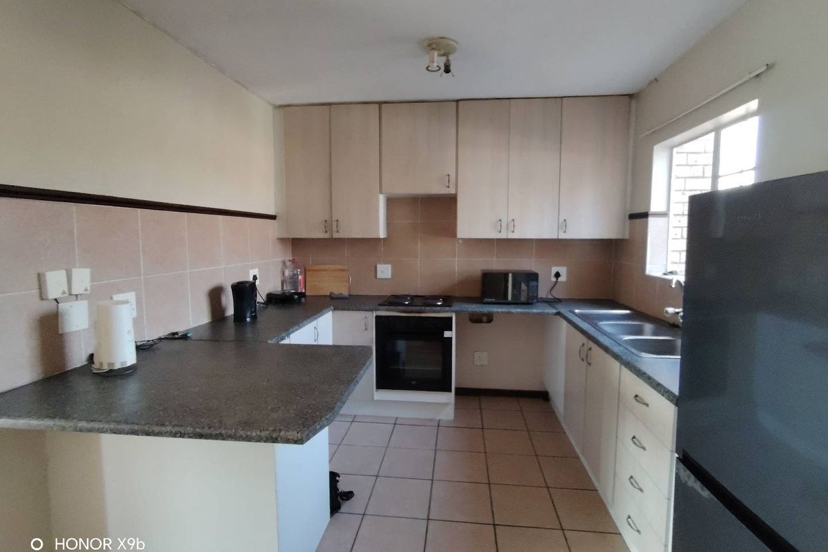 Functional kitchen featuring laminate cabinetry, stone-look countertops, built-in oven, electric hob, and a double bowl stainless steel sink with tiled backsplash.