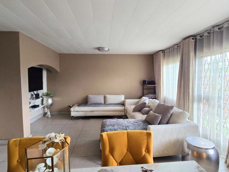 Spacious living room featuring neutral wall tones, large windows with natural light, and tiled flooring throughout.