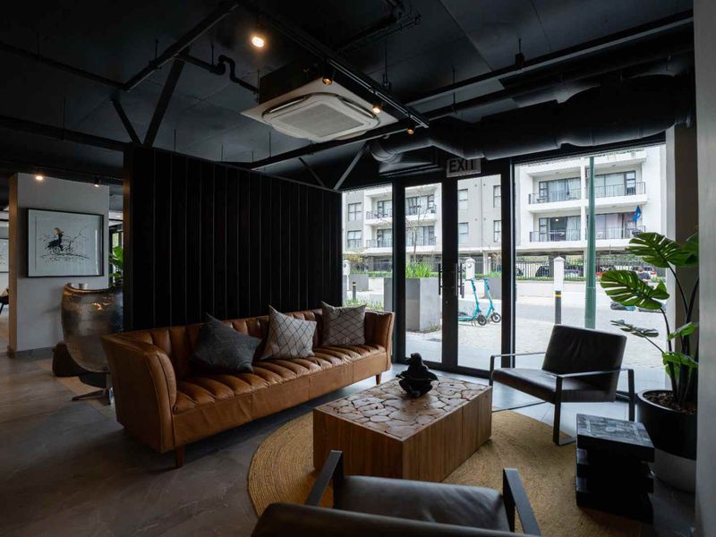 Modern living area featuring an industrial-style exposed ceiling, tiled flooring, and large glass doors providing natural light and access to the exterior.