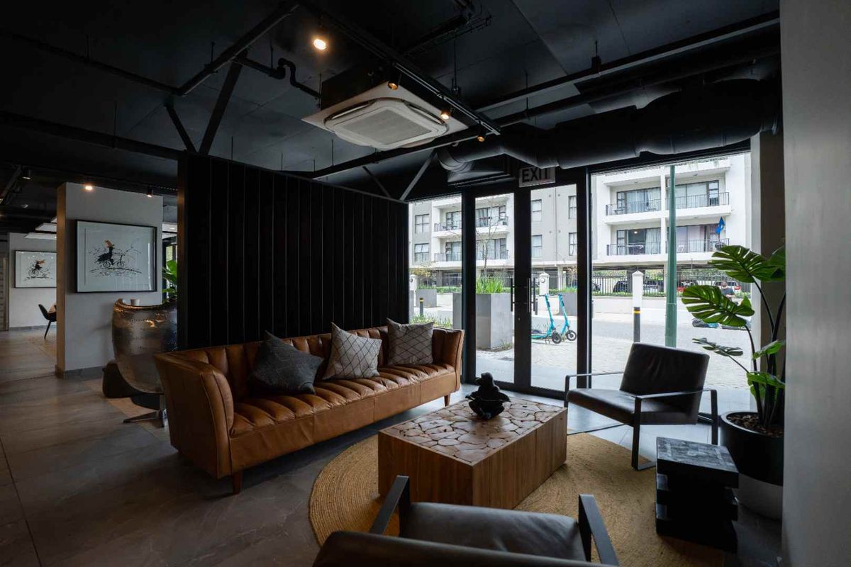 Modern living area featuring an industrial-style exposed ceiling, tiled flooring, and large glass doors providing natural light and access to the exterior.