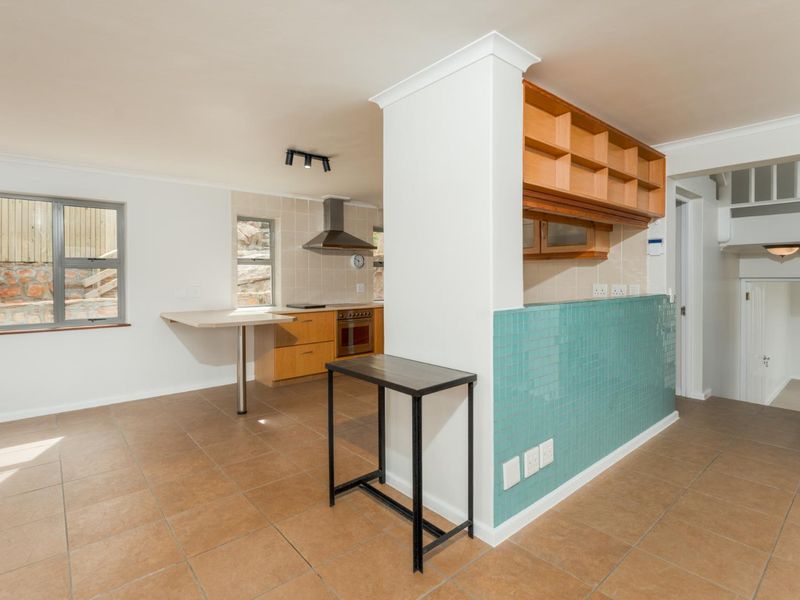 A functional kitchen area featuring built-in wooden cabinetry, a tiled splashback, an integrated oven with extractor fan, and a breakfast bar counter.