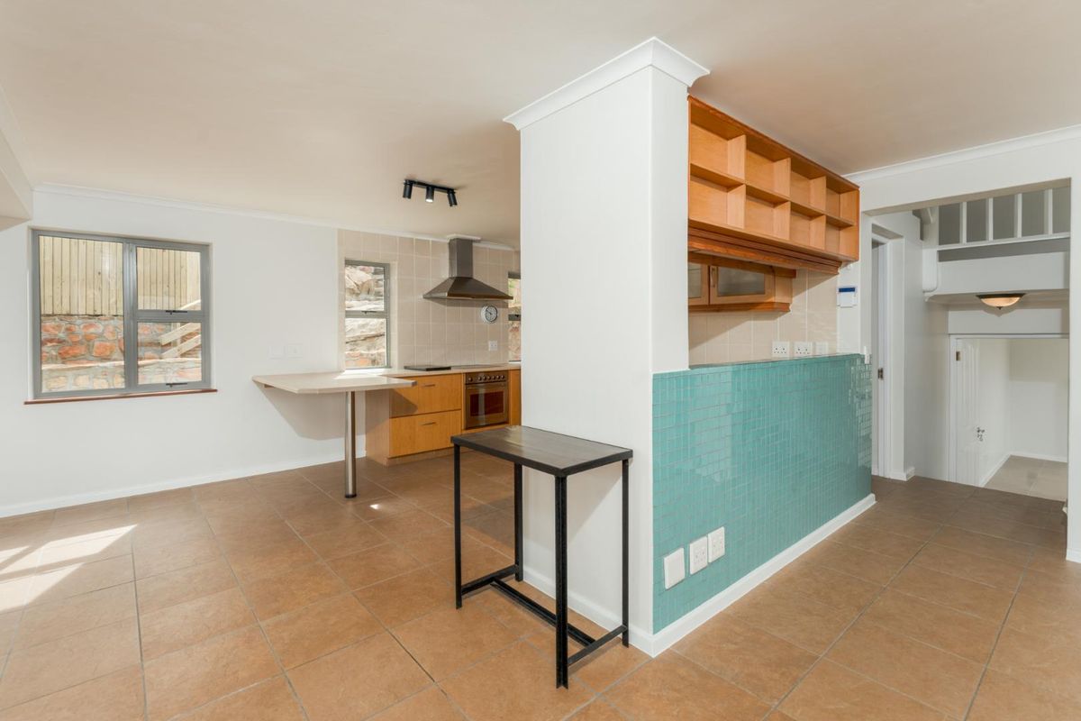 A functional kitchen area featuring built-in wooden cabinetry, a tiled splashback, an integrated oven with extractor fan, and a breakfast bar counter.