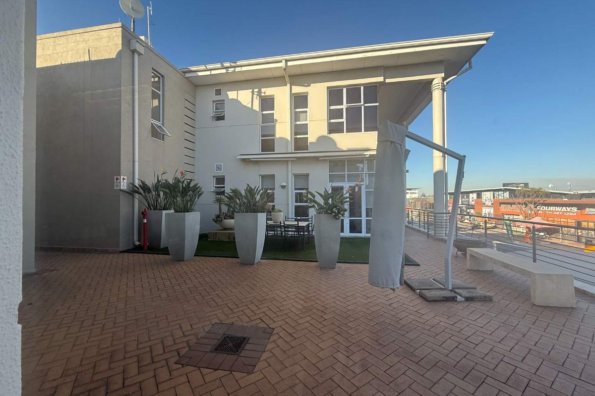 Spacious paved outdoor terrace area featuring a modern building facade, integrated drainage, and perimeter railings, suitable for office break-out space.