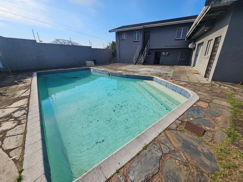 Outdoor pool area featuring a paved patio, external staircase, and boundary wall with electric fencing, requiring maintenance to the pool and surrounding paving.