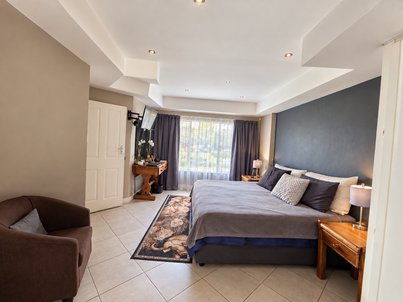 Spacious bedroom featuring tiled flooring, recessed ceiling lighting, and a dark accent wall, creating a comfortable and well-maintained sleeping area.