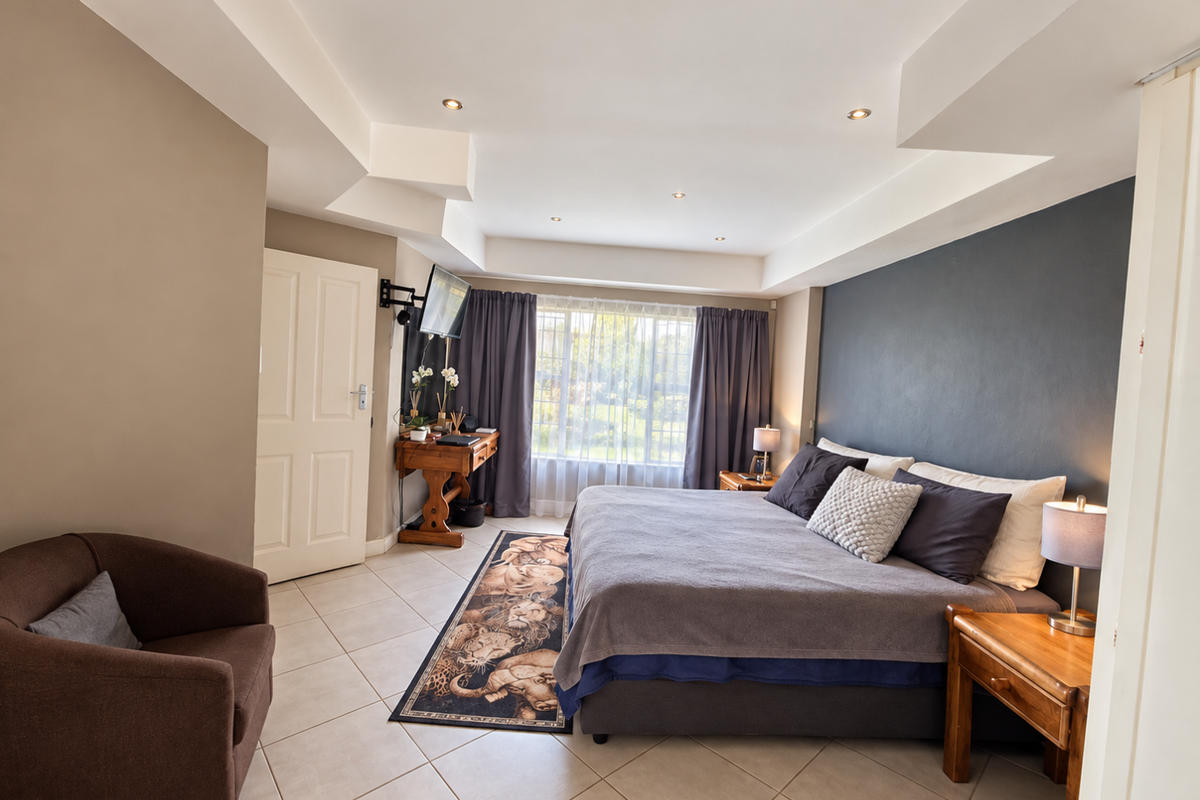 Spacious bedroom featuring tiled flooring, recessed ceiling lighting, and a dark accent wall, creating a comfortable and well-maintained sleeping area.