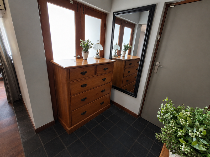 A well-maintained entrance area featuring dark tiled flooring and a timber-framed glass door, providing a clean and welcoming transition into the home.