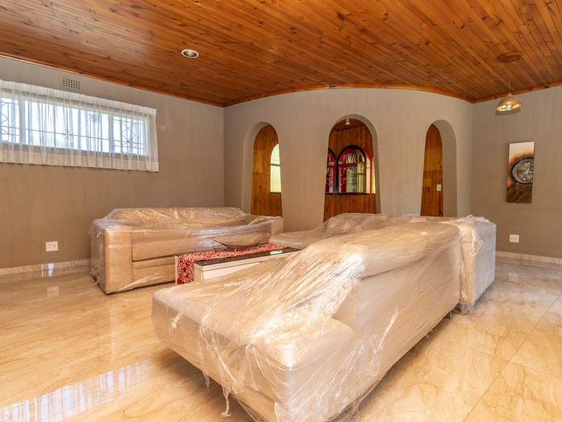 Spacious living room featuring polished tile flooring, a warm timber tongue and groove ceiling, and distinctive arched architectural wall openings.