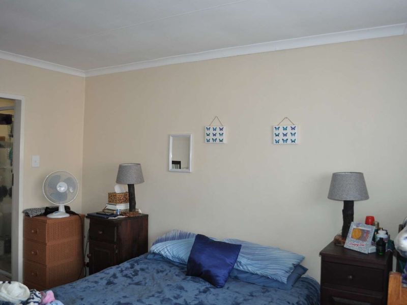 A standard bedroom featuring neutral wall tones, coving, and an adjoining doorway leading to an en-suite bathroom.