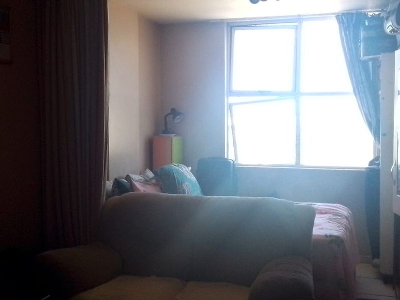 A bedroom featuring a large window with visible frame damage and an integrated air conditioning unit.